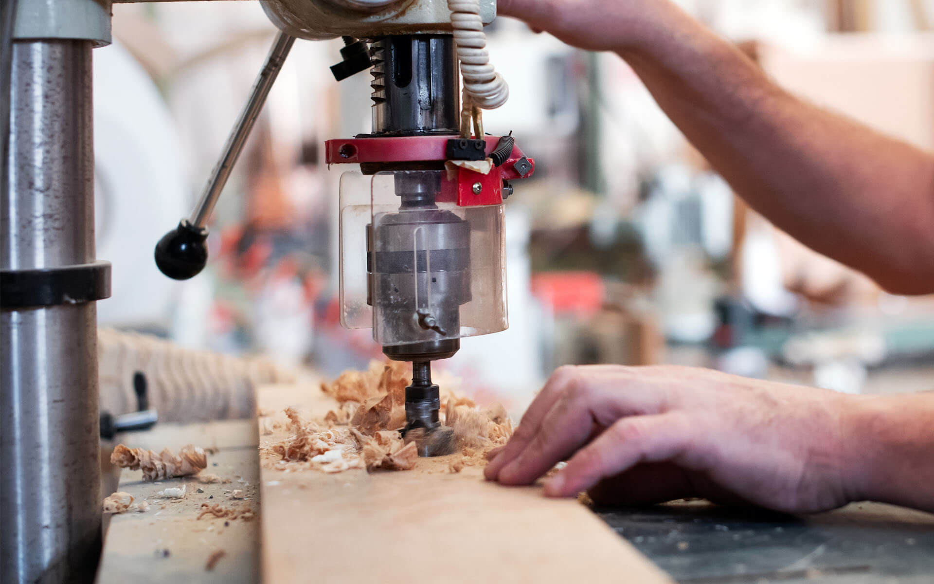Photo of a person using a drill press on a piece of wood